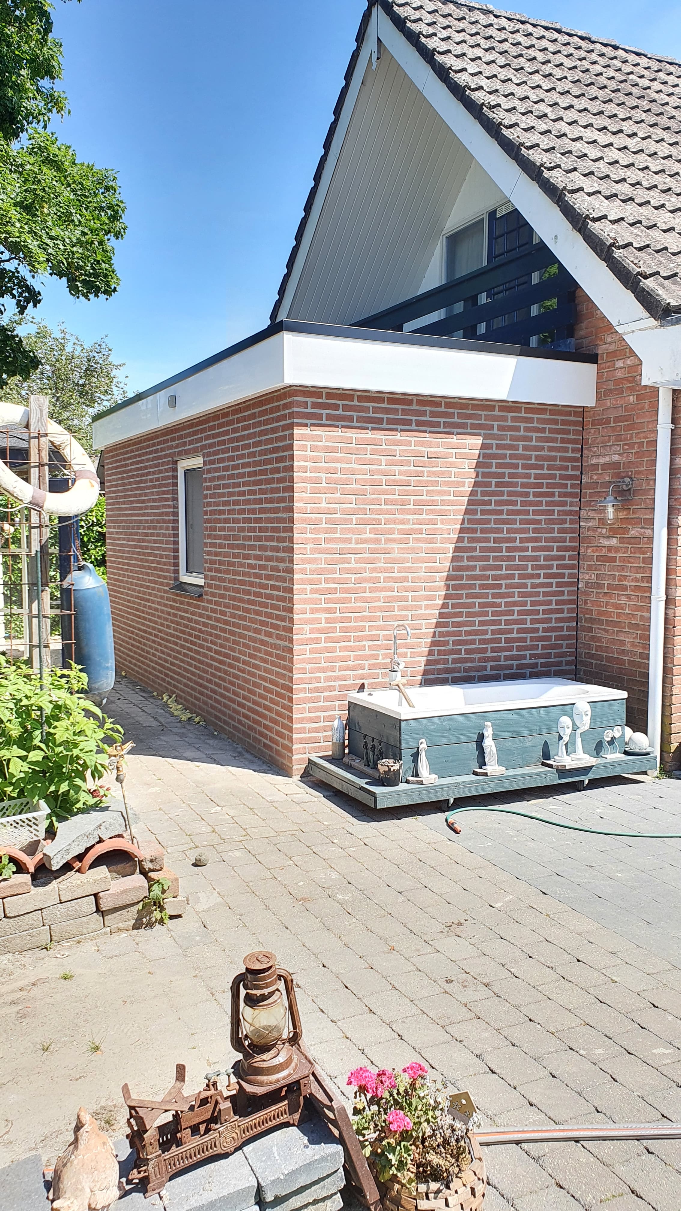 Gemetselde aanbouw met plat dak tegen de bestaande woning
