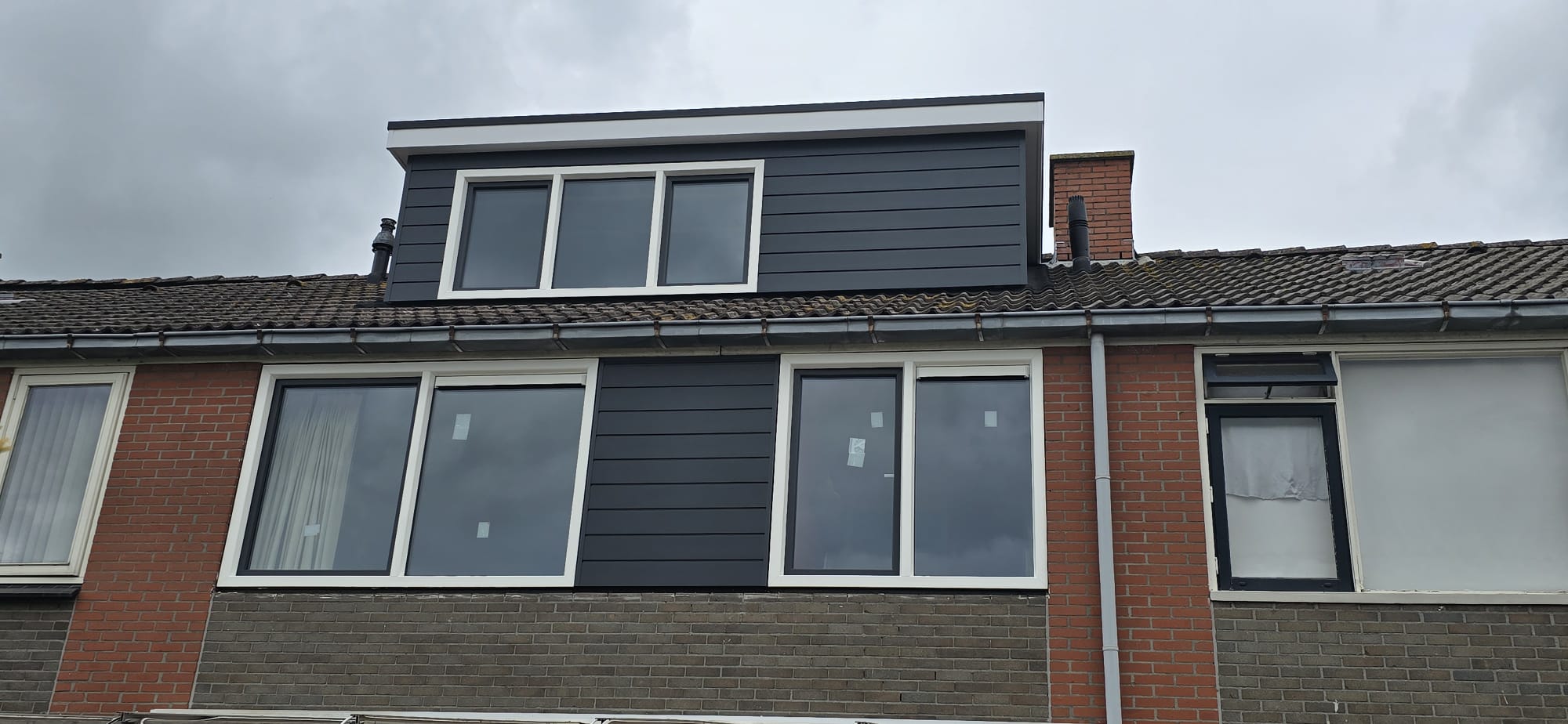 Antracietgrijze dakkapel op het pannendak van een rijtjeswoning